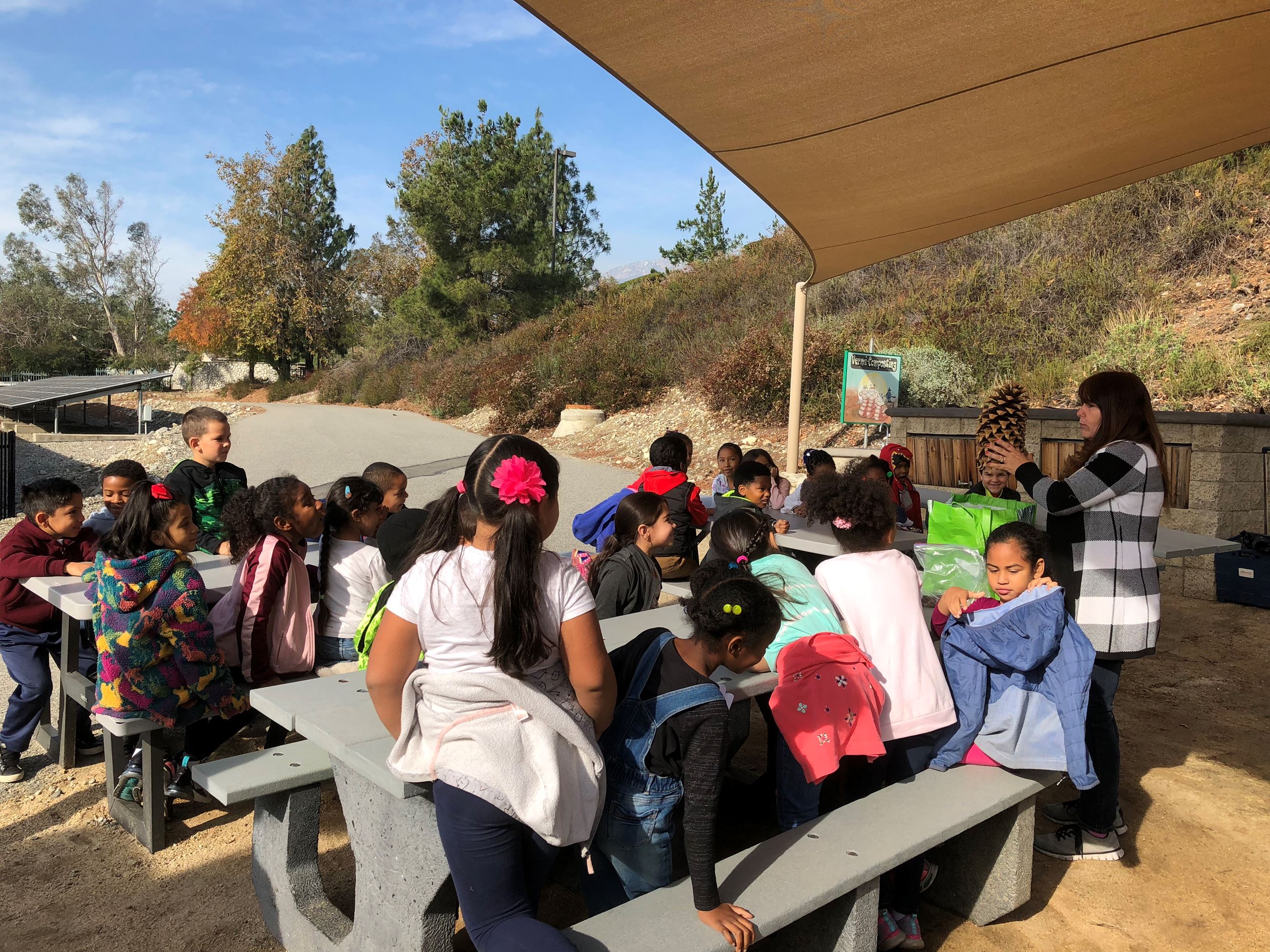 Students sitting outside Environmental Learning Center doing an activity at tables