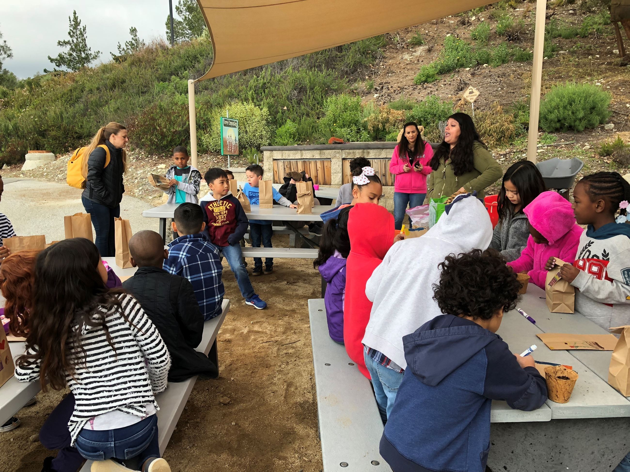 Young children sitting outside at tables doing an activity